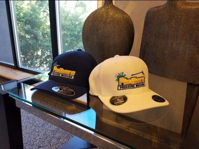 Two hats are sitting on a glass table in front of a window