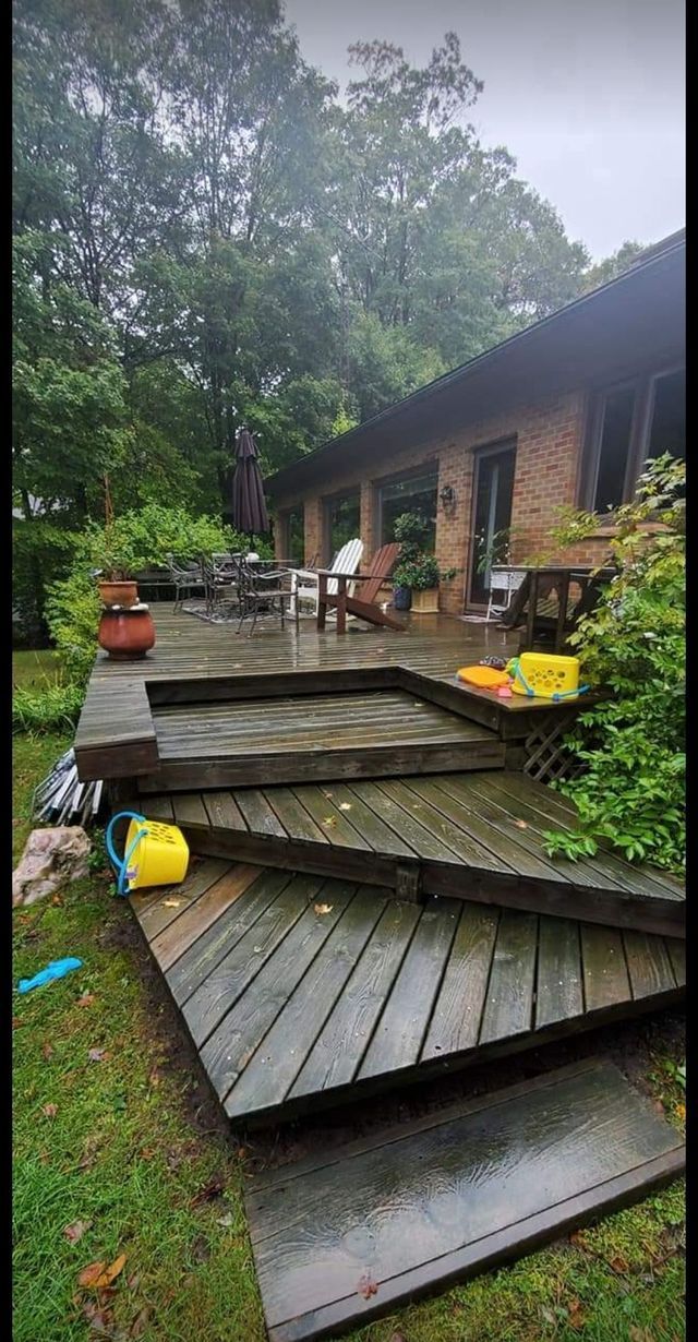 A wooden deck with steps leading up to a house on a rainy day.