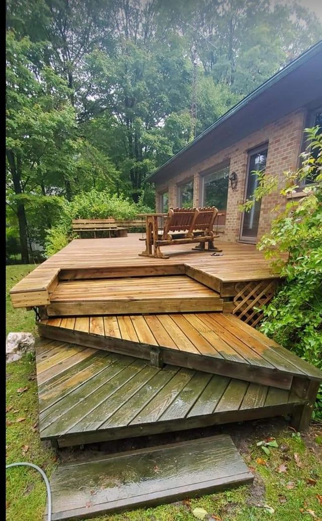A wooden deck with a table and chairs on it in front of a house.