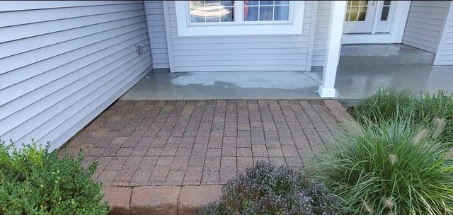 A brick walkway leading to a porch of a house.