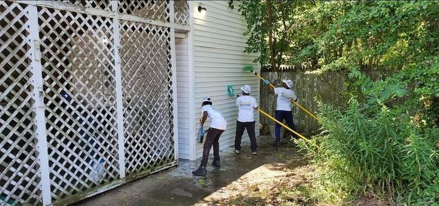 A group of people are cleaning the side of a house.