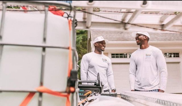 Two men are standing next to each other in front of a house.