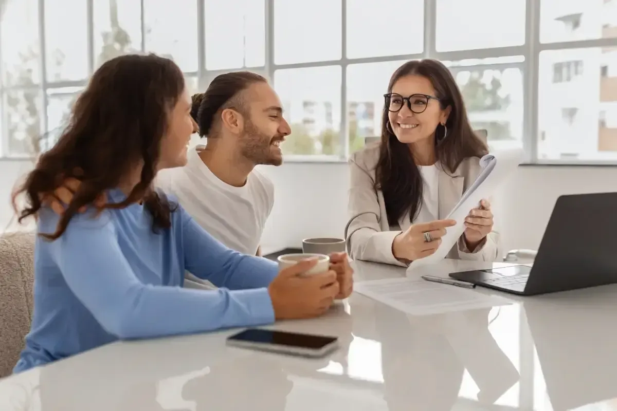 Three coworkers discussing ideas around a laptop during a meeting at an office table.