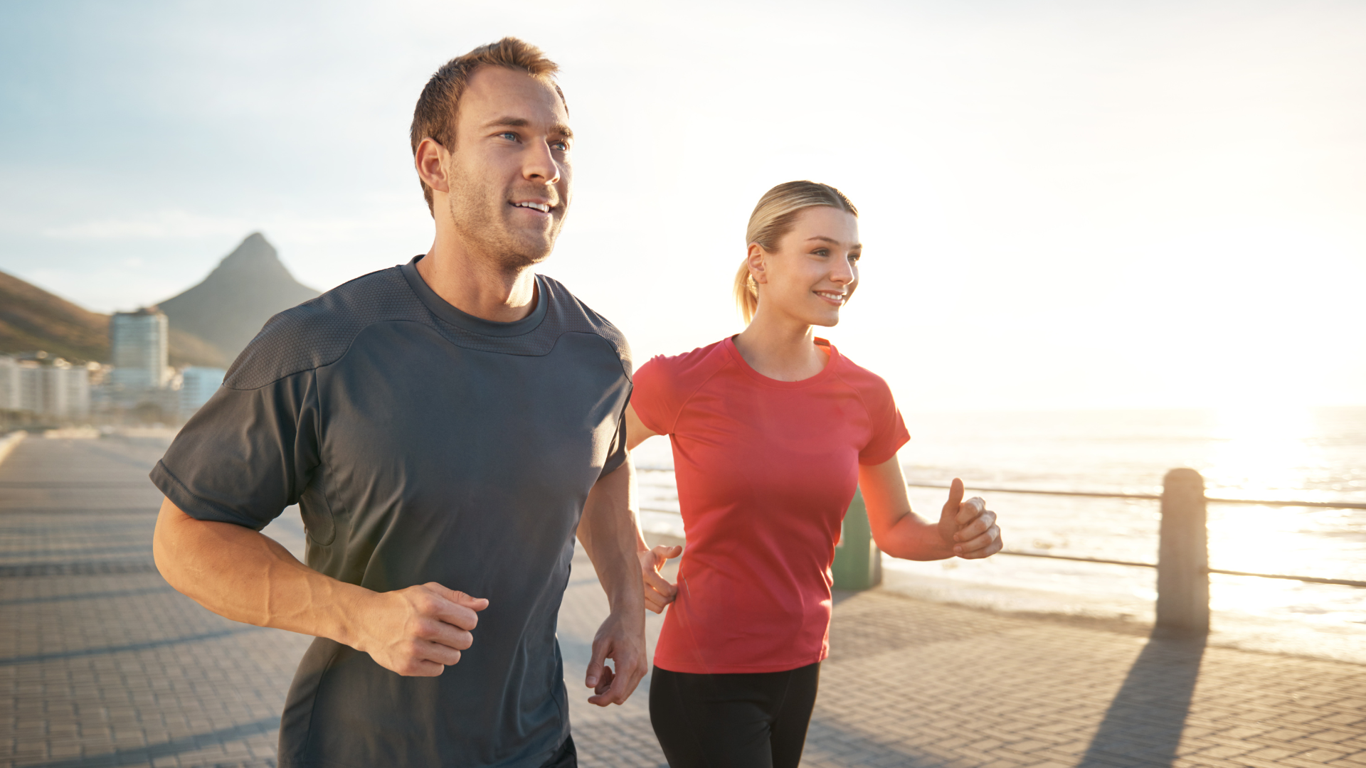 A man and a woman are jogging on the beach.