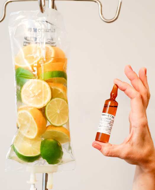 A person is holding an ampoule next to a bag of fruit