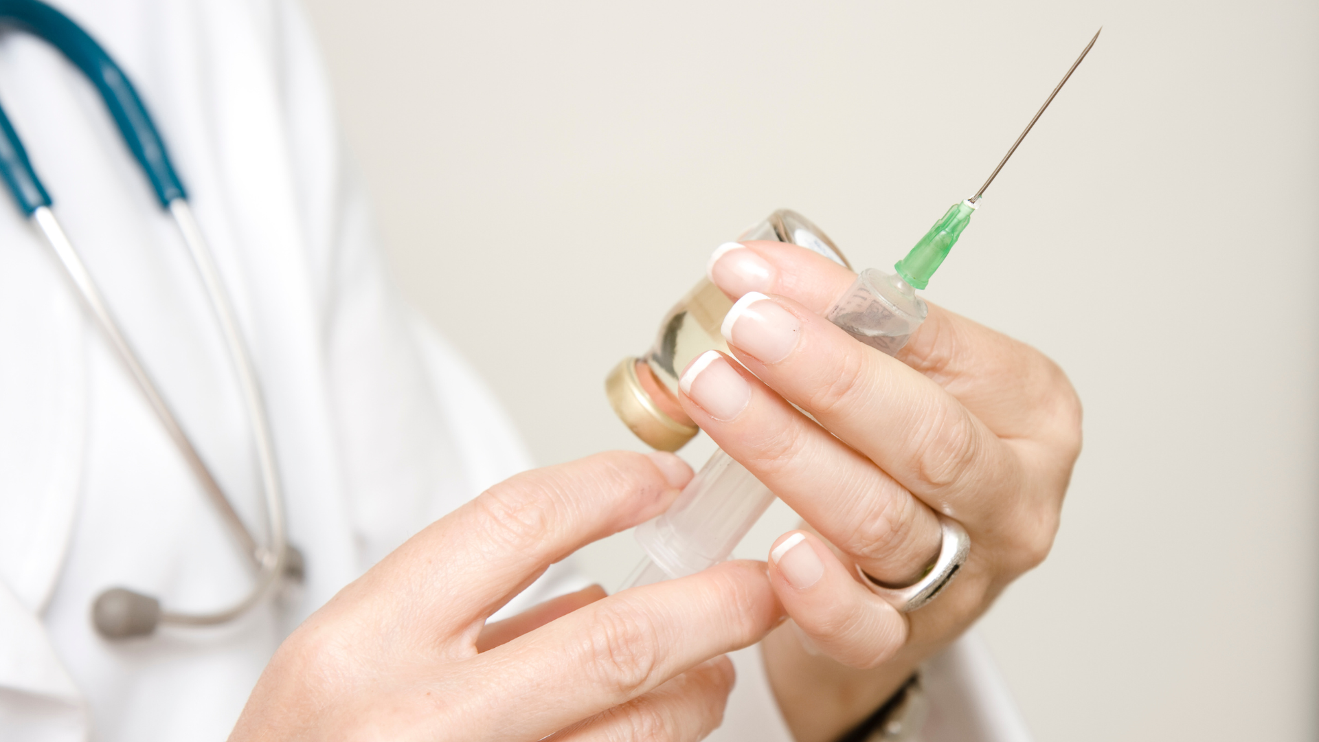A doctor is holding a syringe and a bottle of medicine.