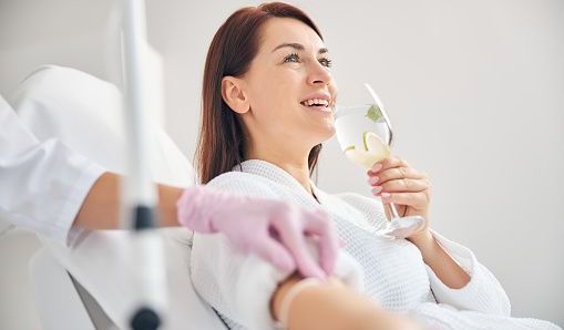 A woman is sitting in a chair holding a glass of wine.