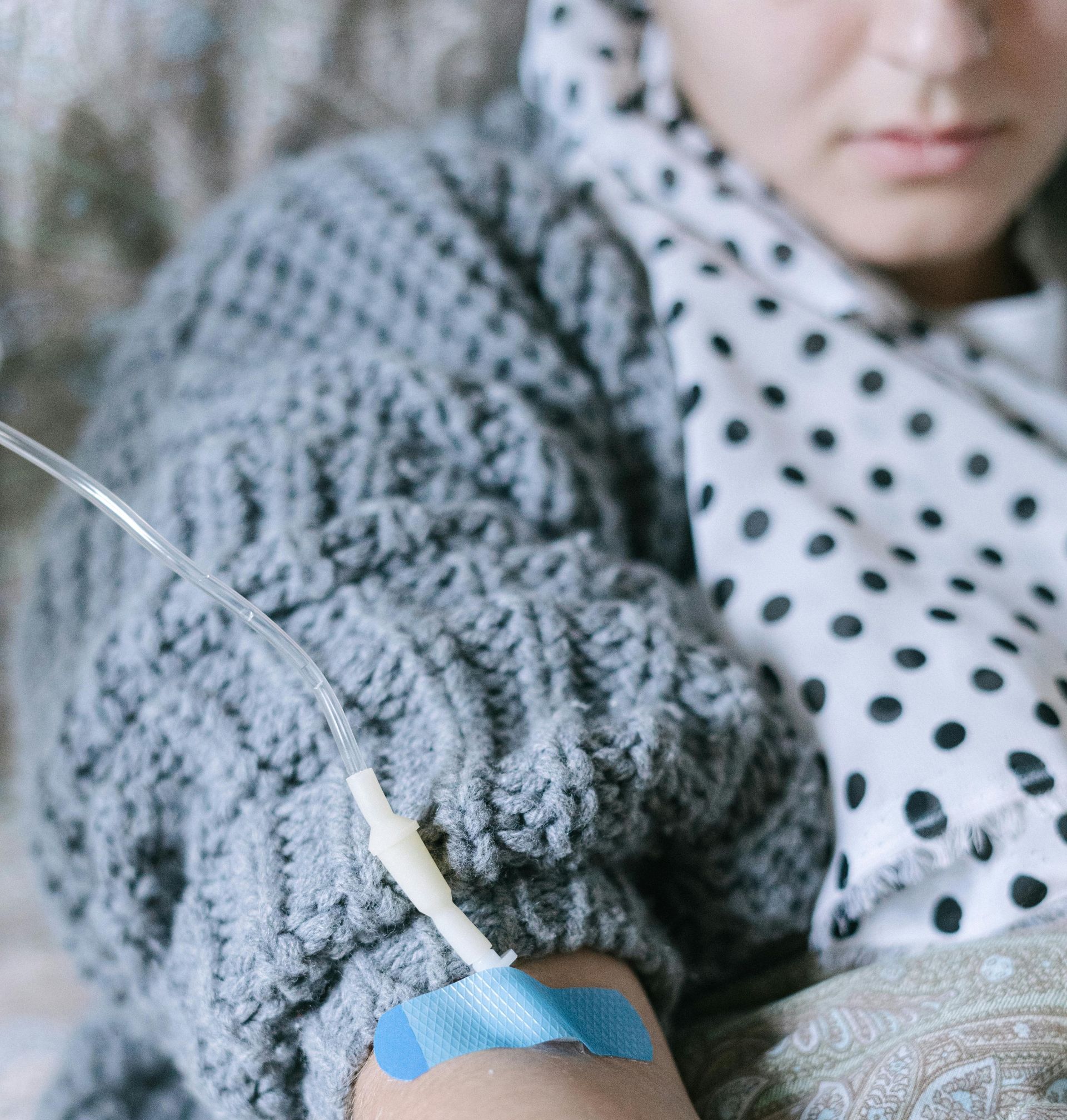 A woman is laying on a couch with an iv in her arm.