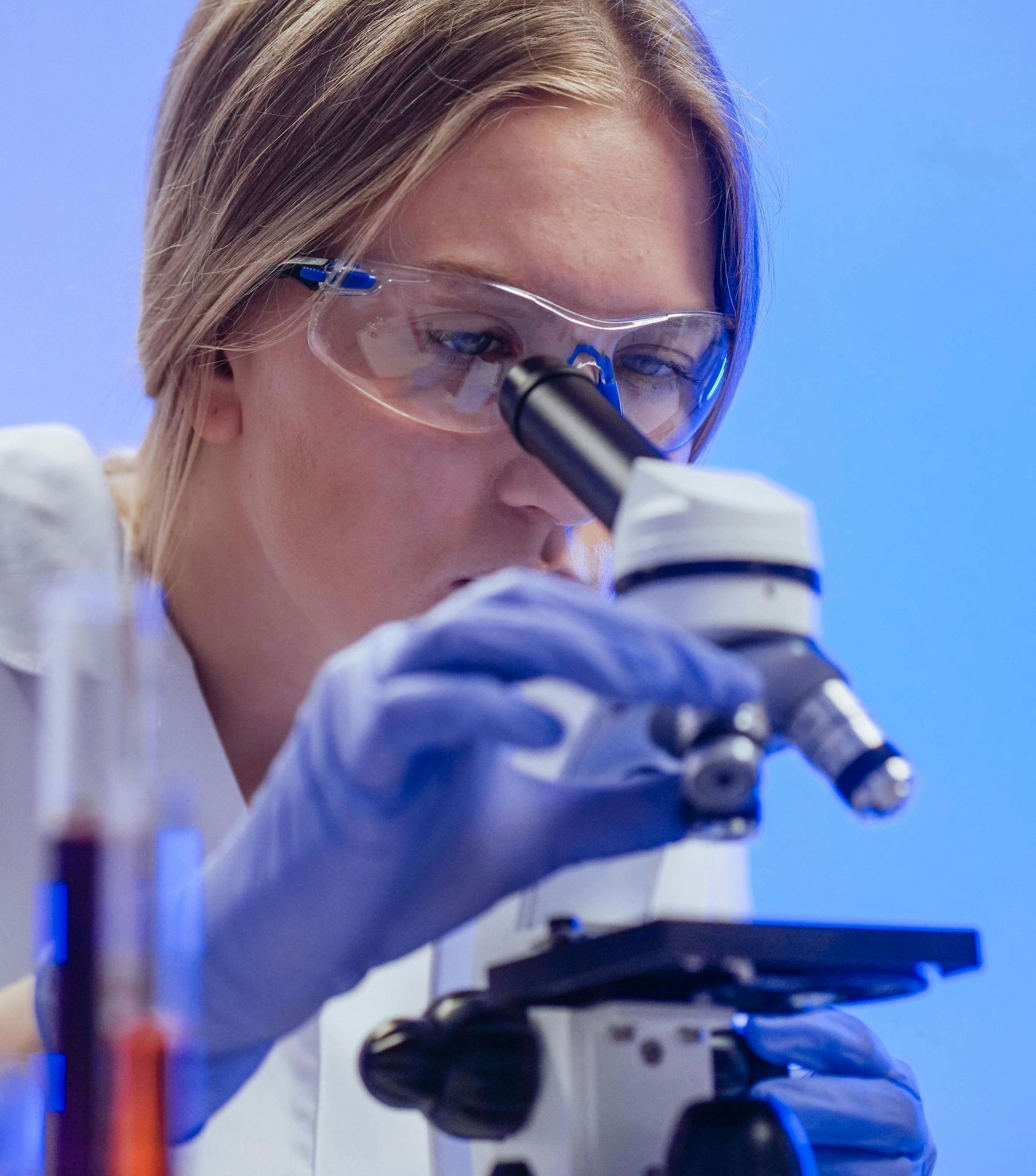 A woman is looking through a microscope in a laboratory.