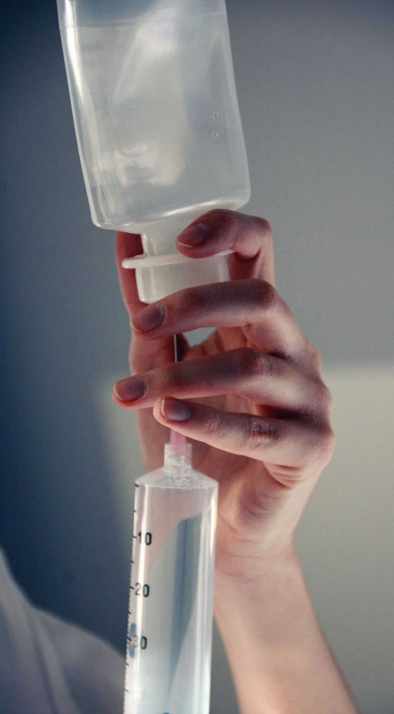 A person is holding a syringe and a bottle of liquid.