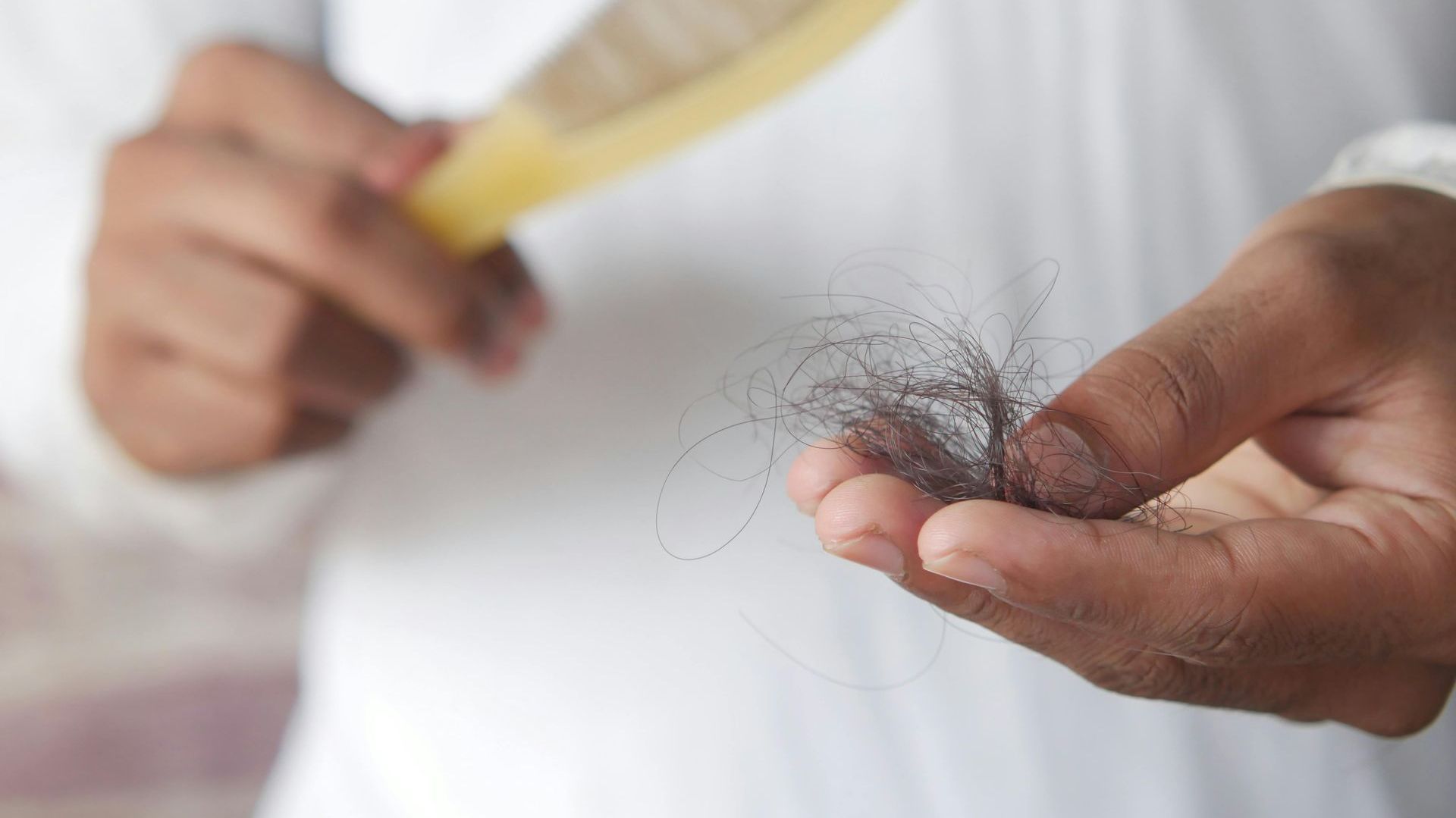 A person is brushing their hair with a comb.