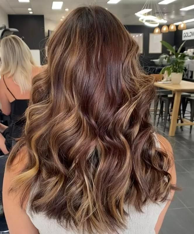 Woman with brown hair styled in voluminous waves, highlighting golden and light brown streaks — Eden Hair in Pacific Paradise, QLD