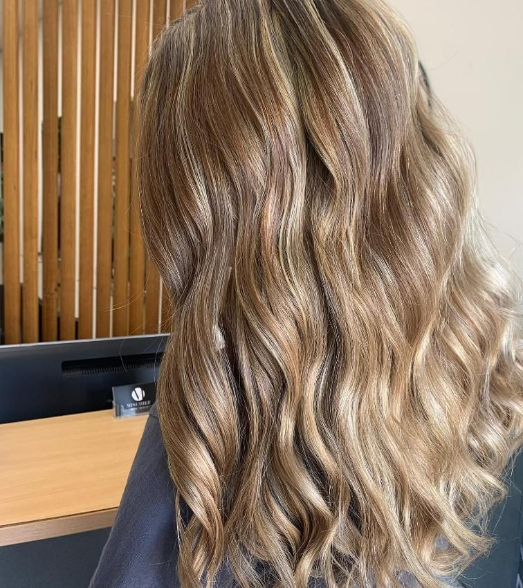 A Woman with Long Wavy Hair Is Sitting in Front of A Computer — Eden Hair in Pacific Paradise, QLD