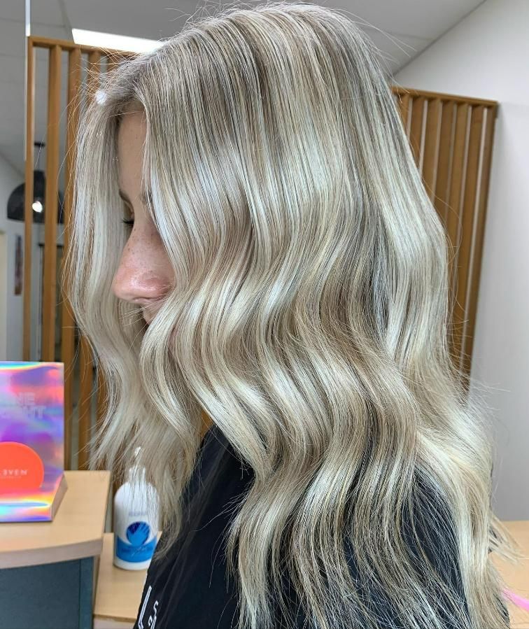 A Woman with Long Blonde Hair Is Standing in A Salon — Eden Hair in Pacific Paradise, QLD
