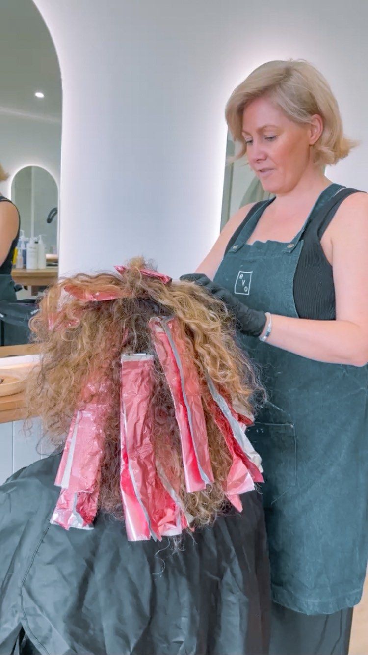 Blonde woman coloring hair with foils in a salon — Eden Hair in Pacific Paradise, QLD
