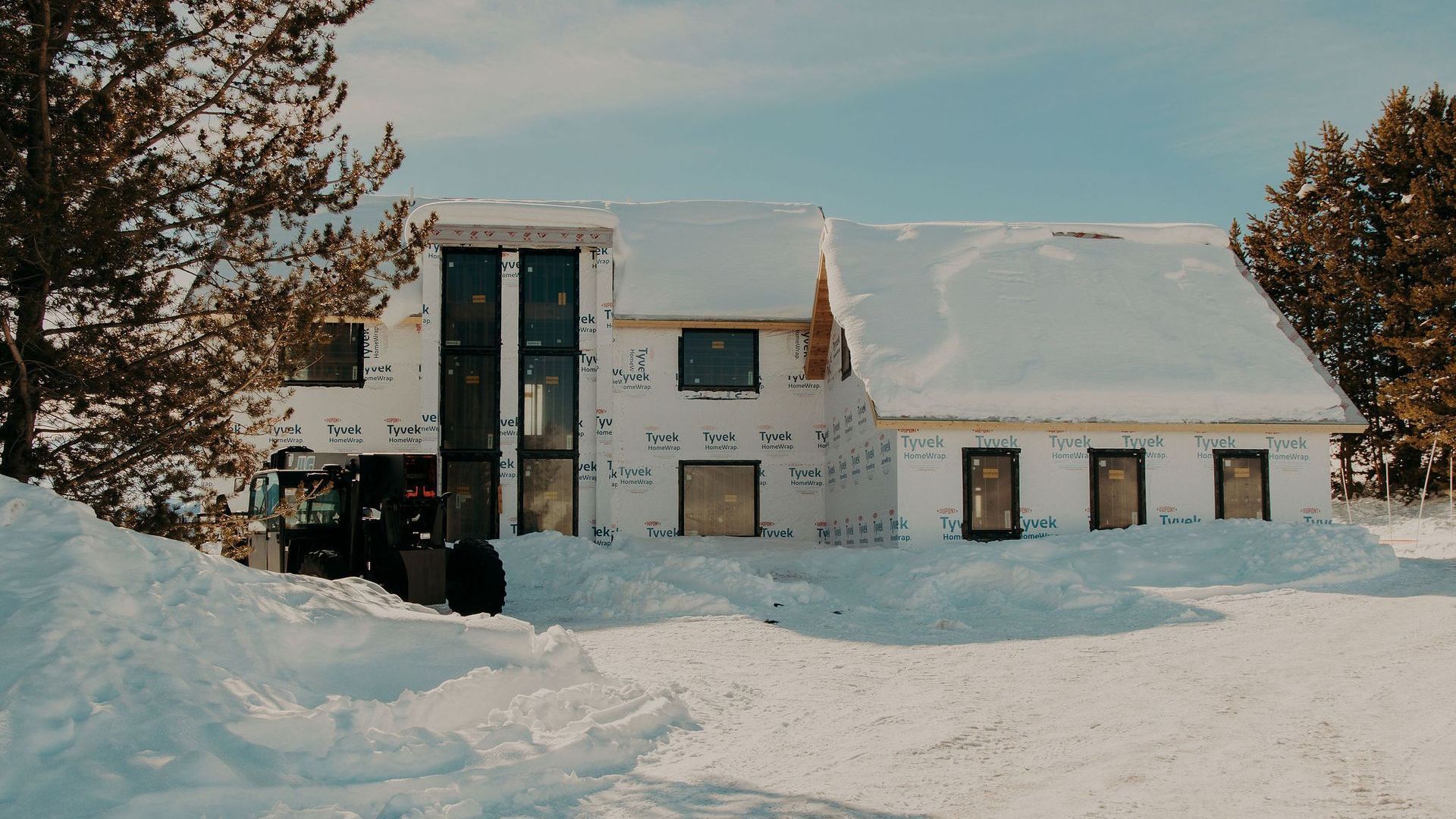 A house under construction is covered in snow.