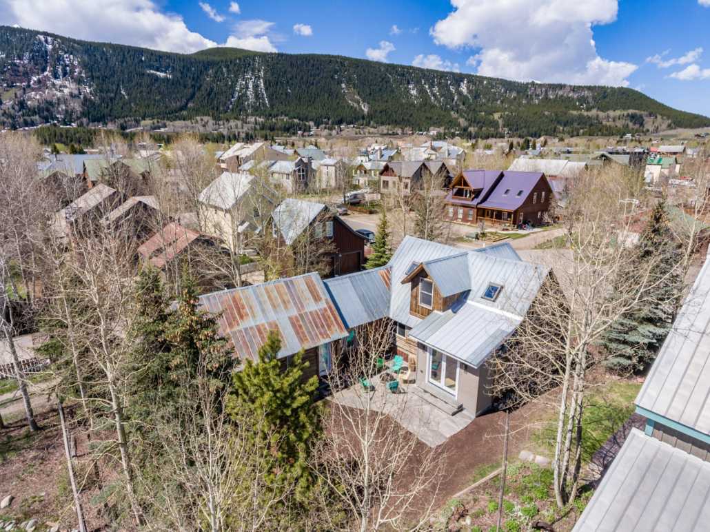 an aerial view of a house in a small town with mountains in the background .