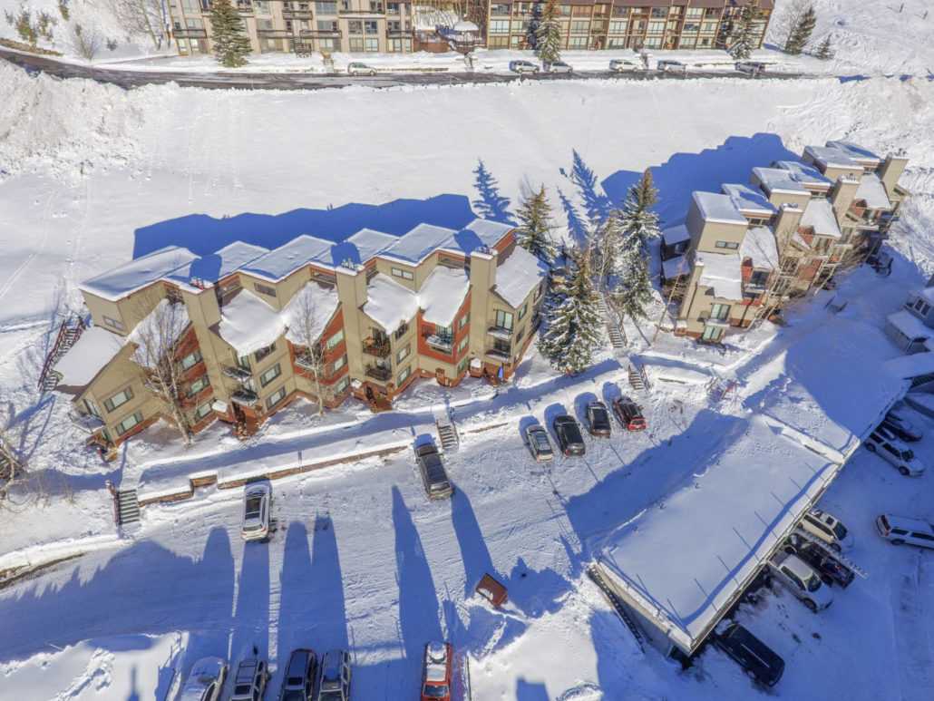 an aerial view of a snowy area with buildings and cars parked in the snow .