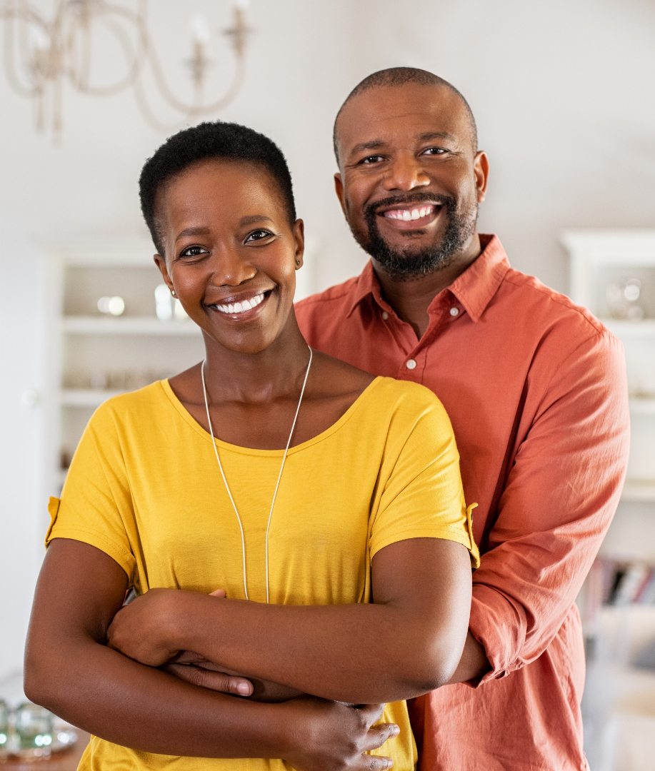 Two smiling people standing indoors with arms crossed, wearing yellow and orange tops.