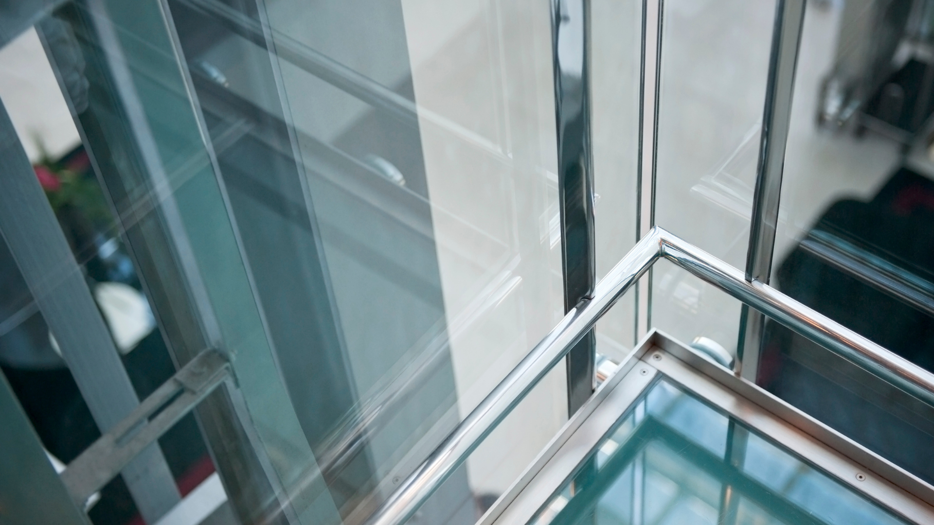 Glass and metal stairwell with reflective surfaces and angular design.