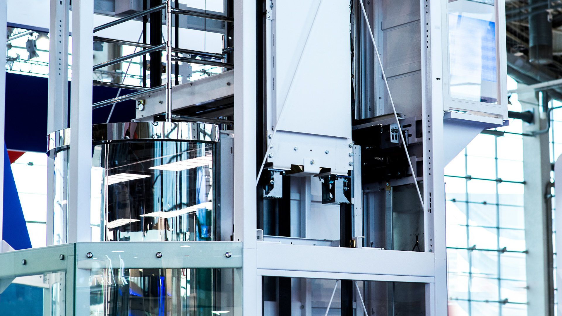 Elevator with glass walls, steel frame, and mechanical components visible.