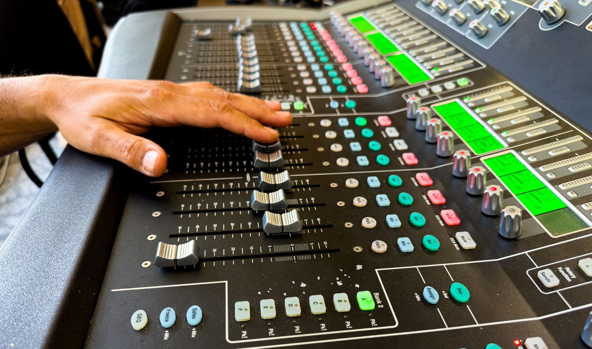 AV rental soundboard with technician adjusting audio levels on professional mixer.