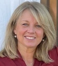 A woman in a red coat is standing in front of a white background.