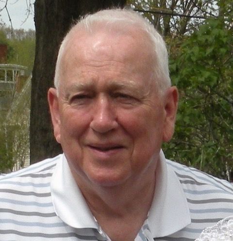 A man with a beard is wearing a red polo shirt and smiling.