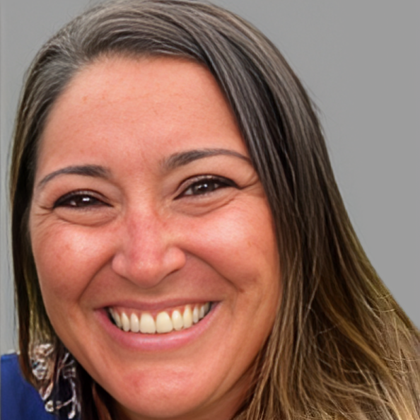 A woman in a tan coat is smiling for the camera.