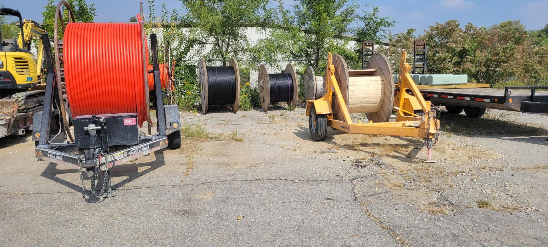 Several cable spools and a trailer, outdoors.