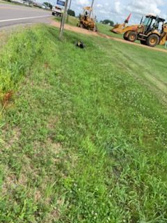 Grassy roadside with construction equipment. A backhoe and a front-end loader are visible on the right.
