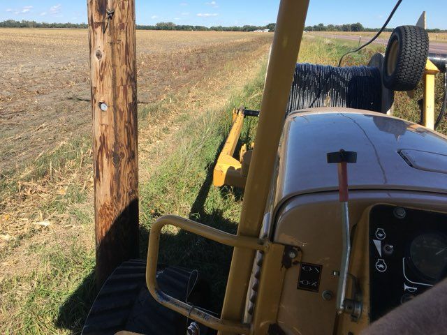 Yellow tractor in ditch, near a utility pole and field. Tire mounted on equipment.