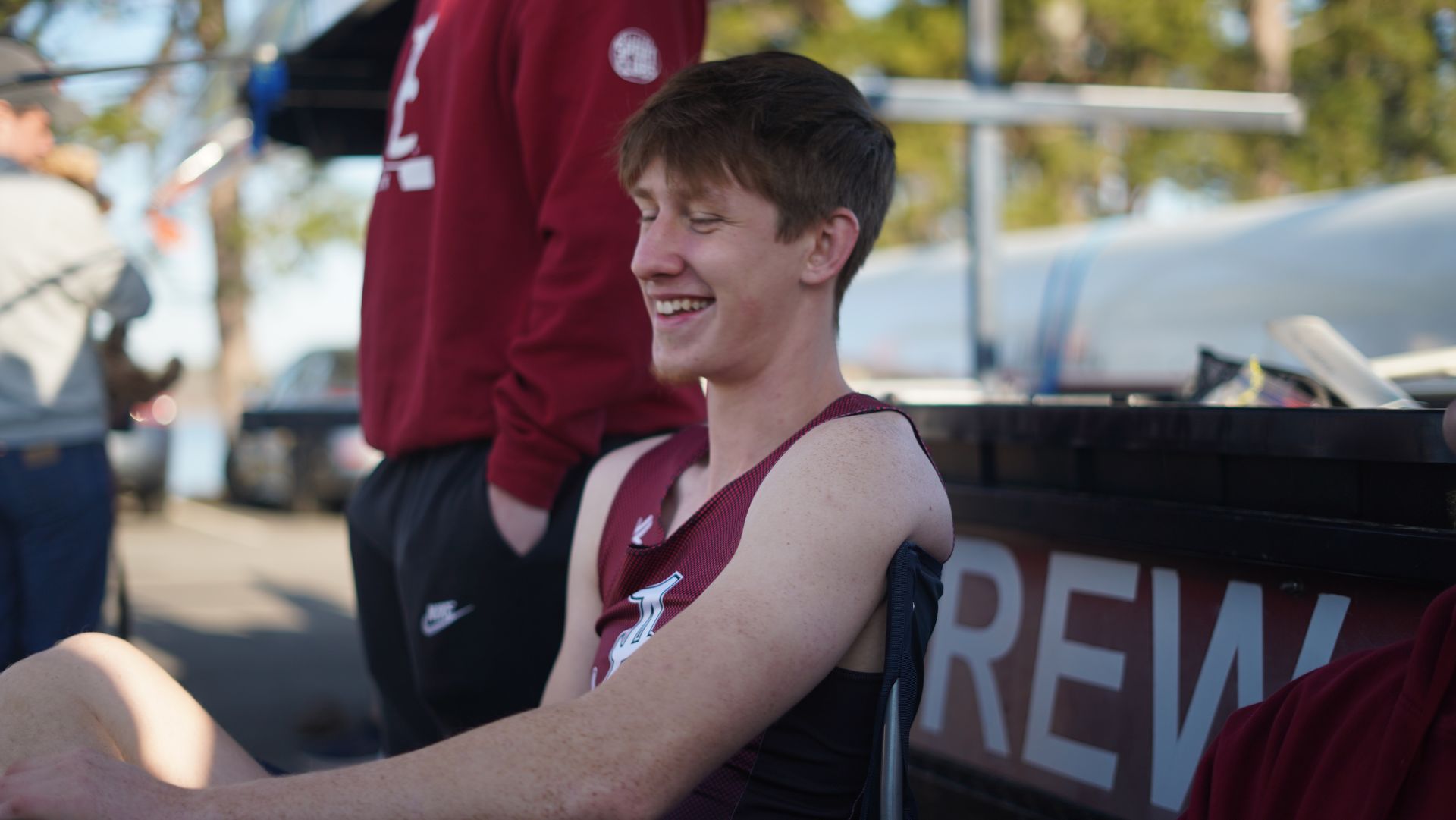 Smiling young man in maroon athletic wear sitting at a 