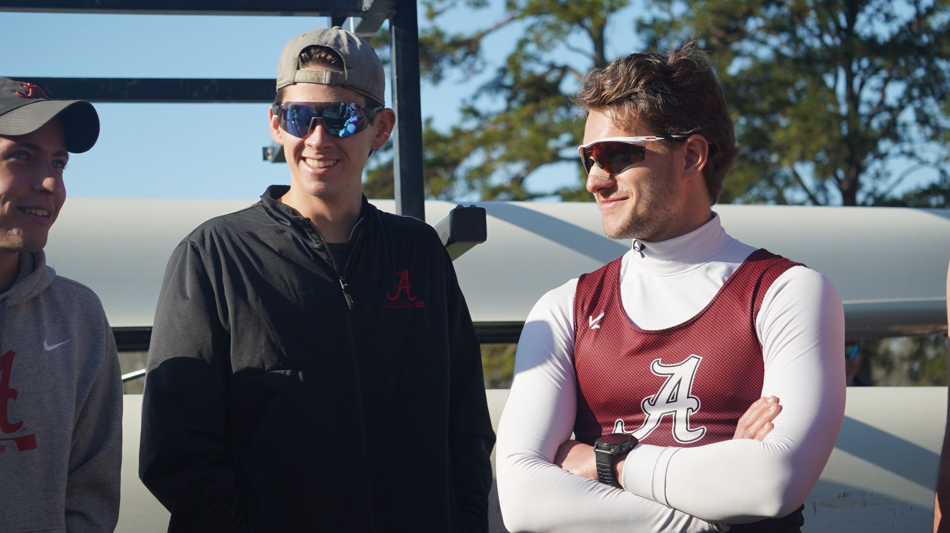 Three men wearing sunglasses and Alabama apparel stand outside. One man crosses his arms, smiling.