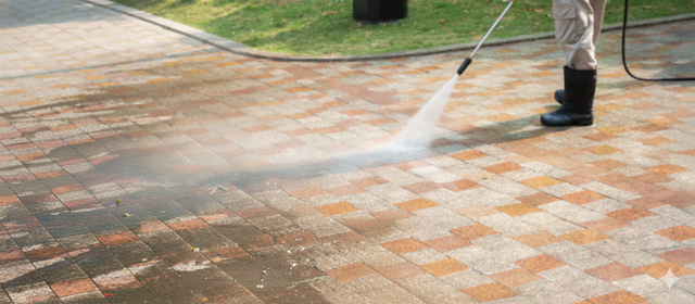 Person power washing a brick patio.