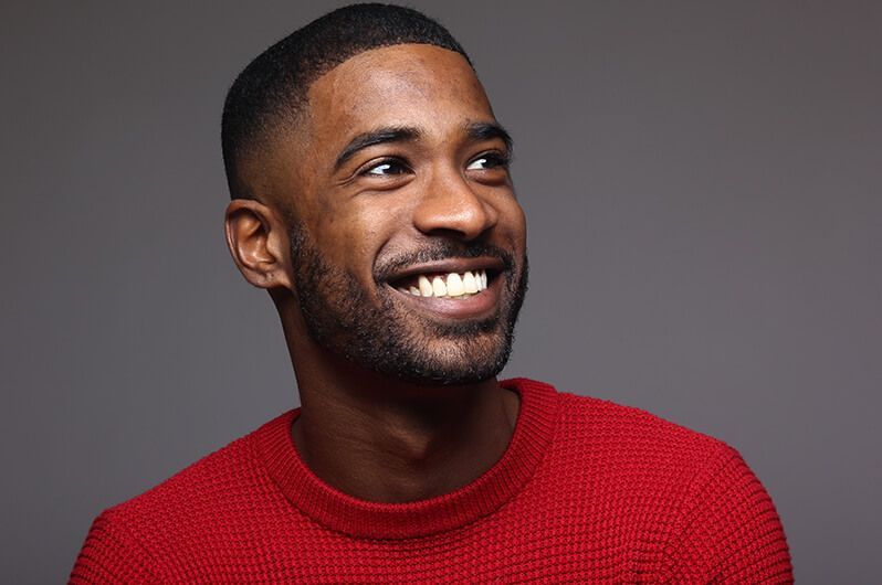 A man with a beard is wearing a red sweater and smiling.