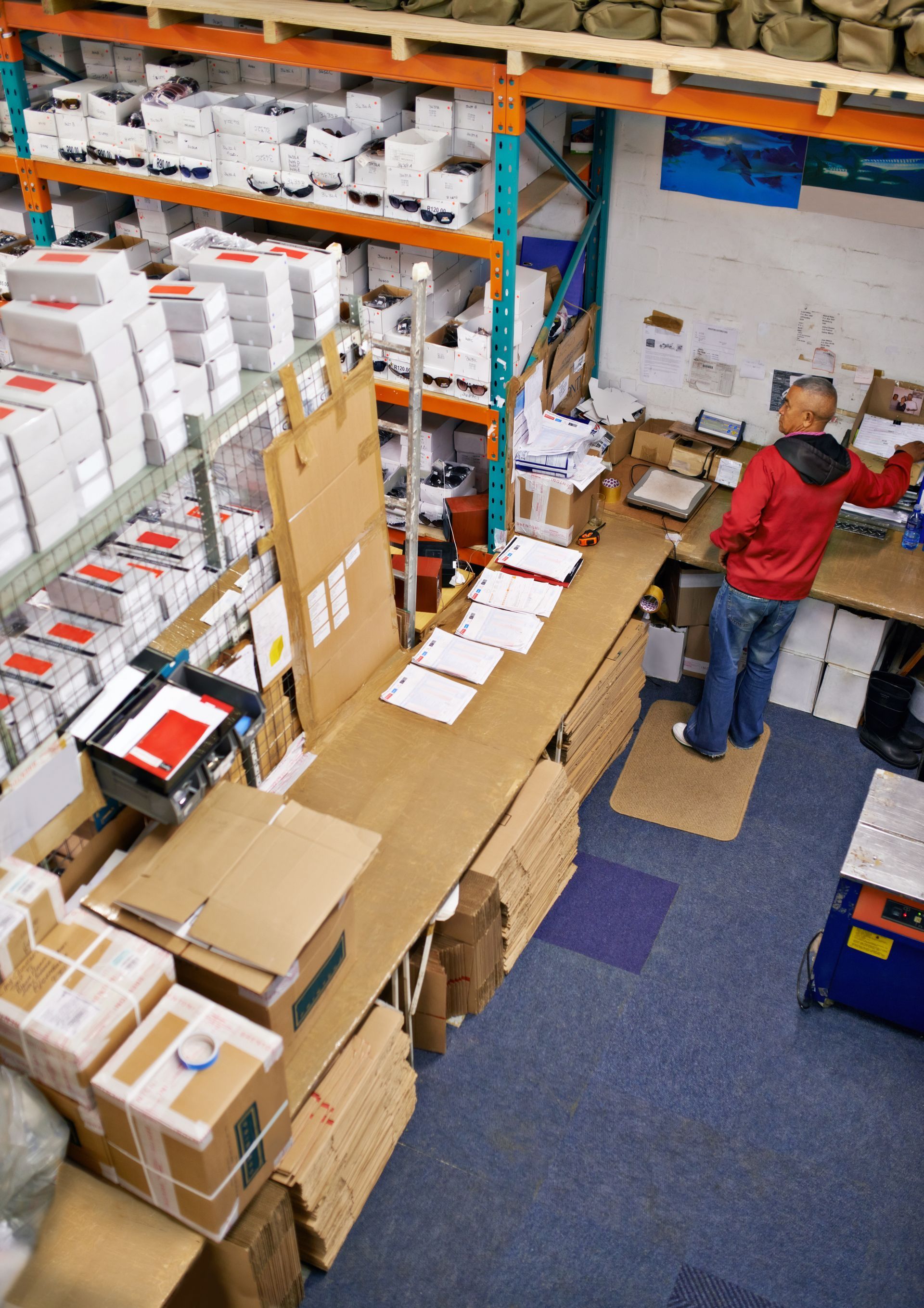 A man in a red jacket is working in a warehouse