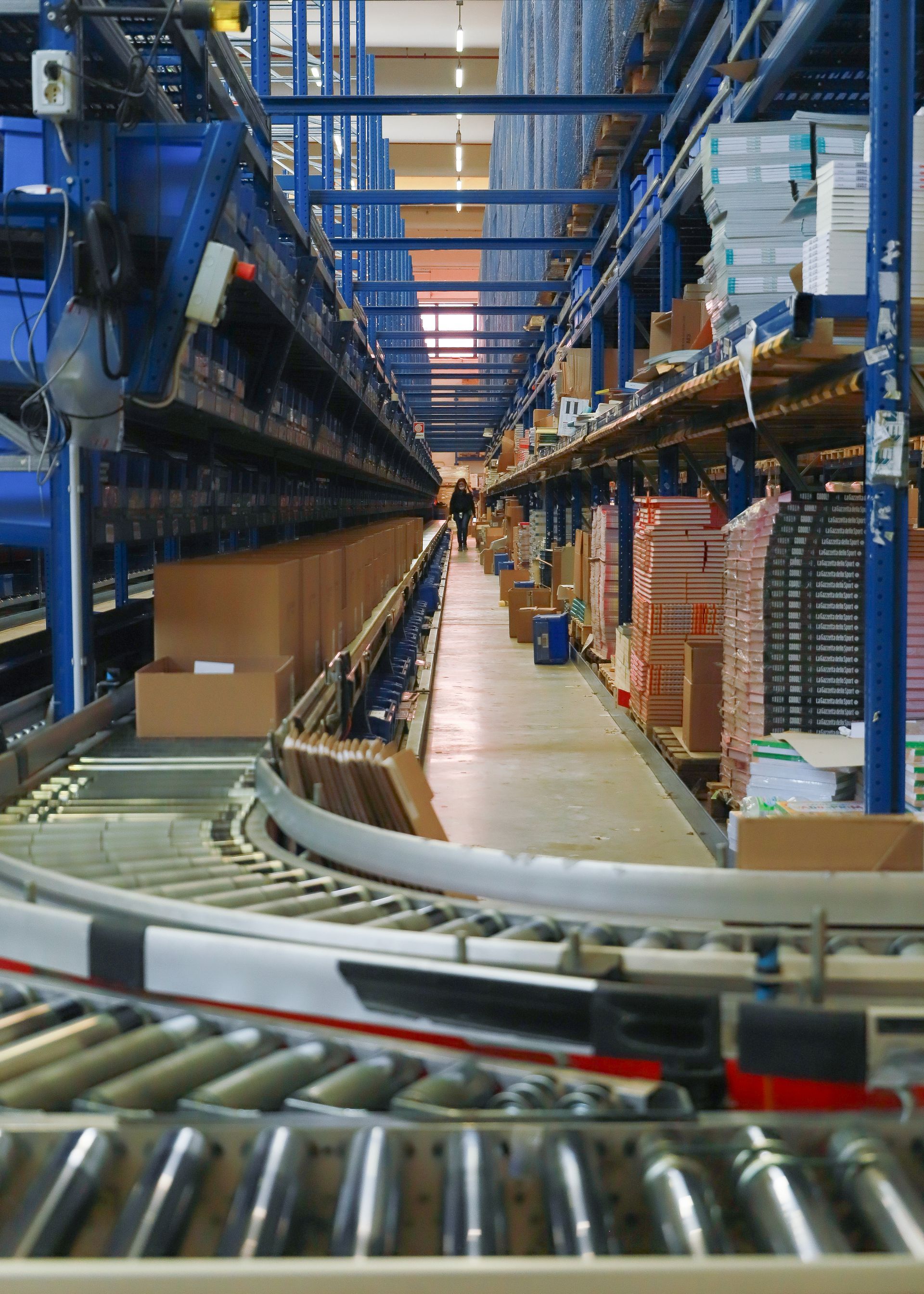 A conveyor belt is in the middle of a warehouse filled with boxes.
