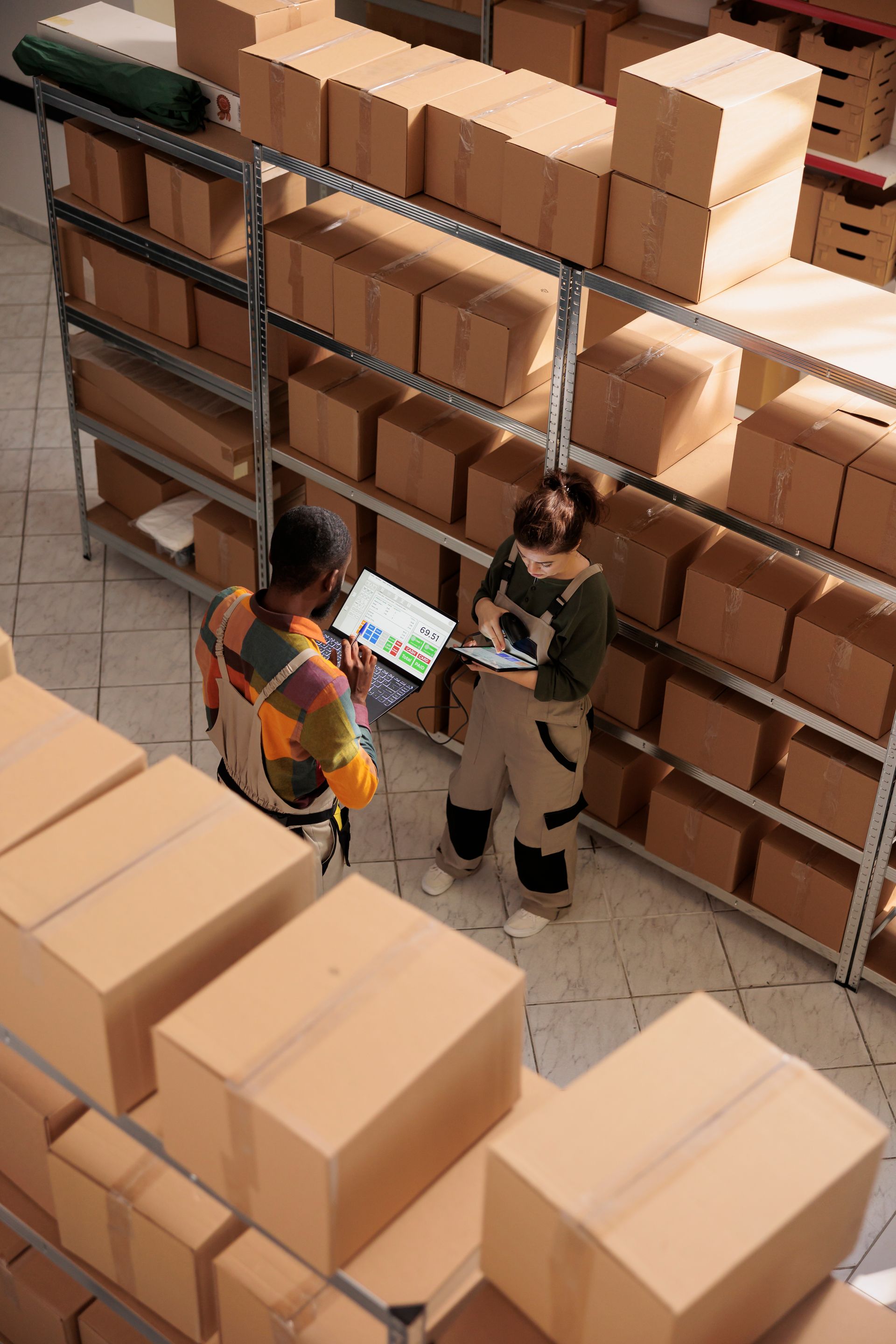 Two people are standing in a warehouse looking at a tablet.