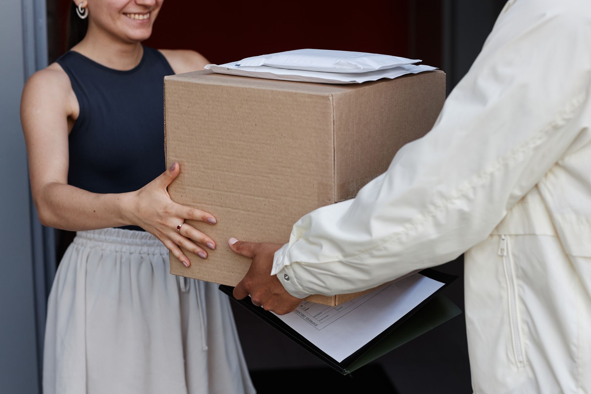 A woman is receiving a box from a delivery man.