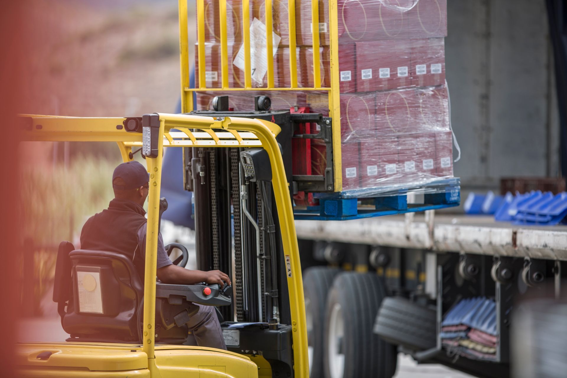 A man is driving a forklift in front of a truck.