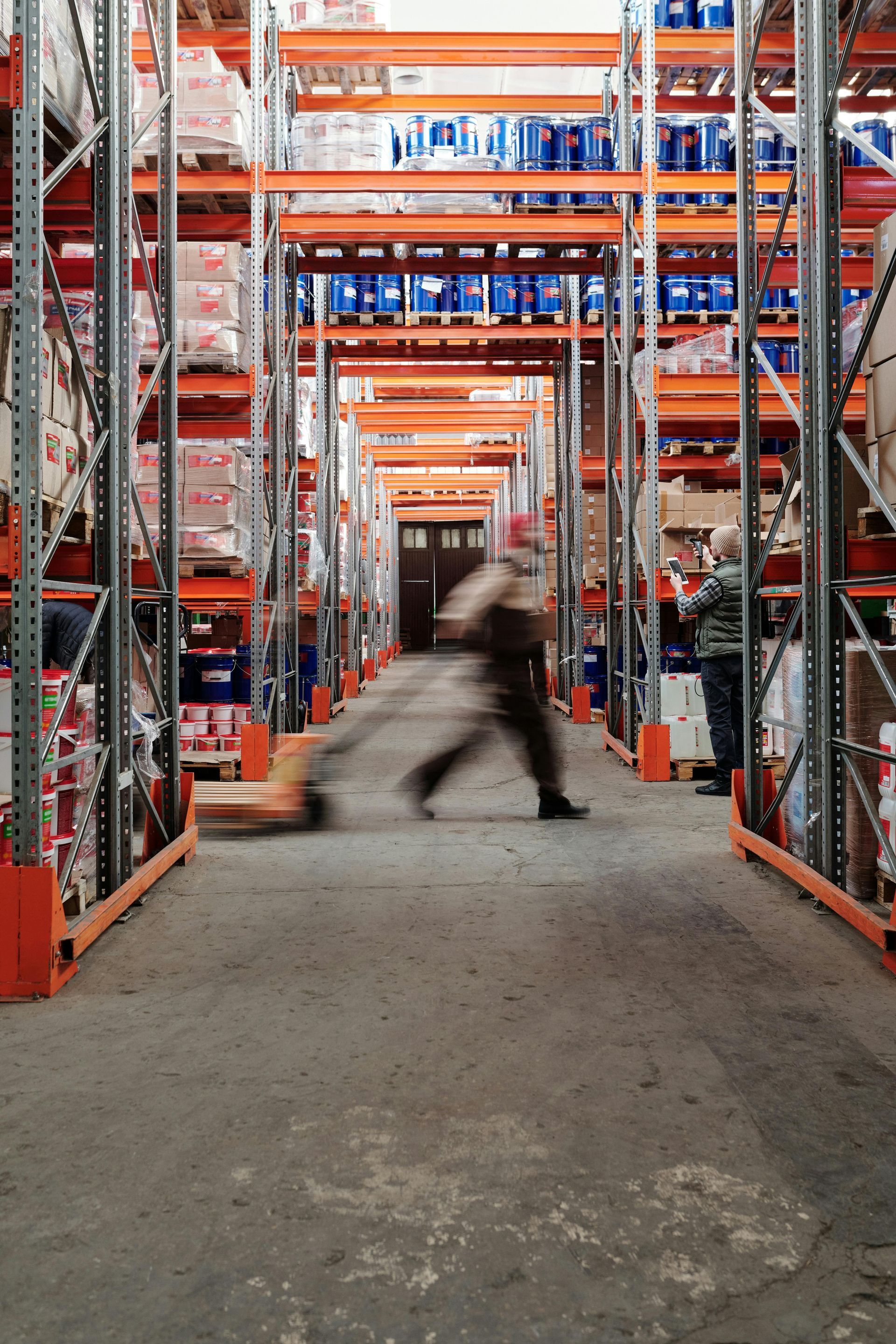 Worker walking through an e-commerce warehouse with tall metal shelving filled with inventory