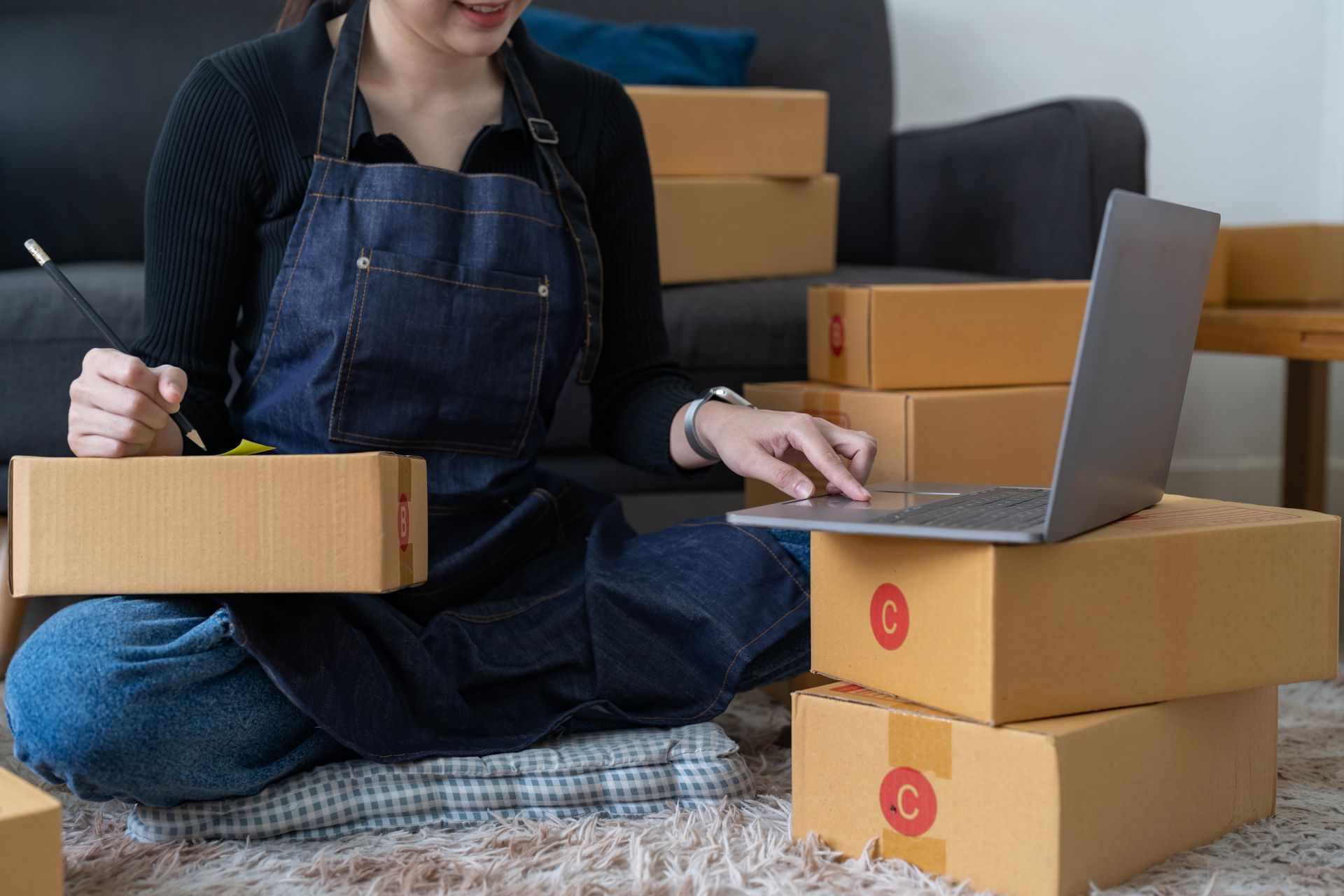A woman is sitting on the floor with boxes and a laptop.