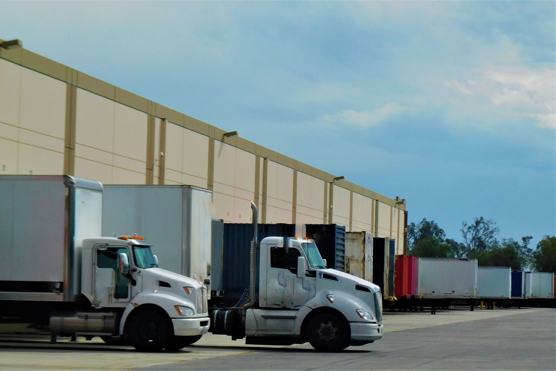 Two semi trucks are parked in front of a building