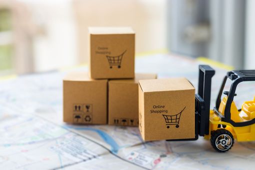 A toy forklift is carrying a stack of cardboard boxes on a map.