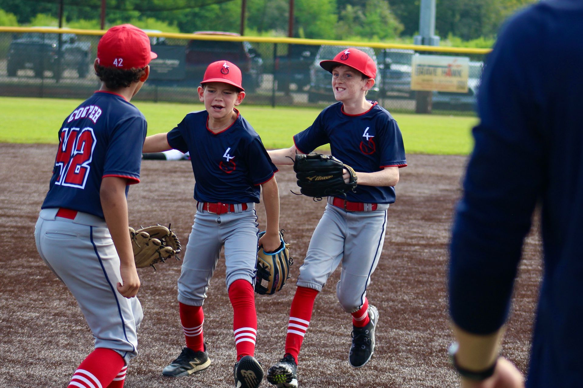 Softball equipment: bat, helmet, glove, and balls on a dirt infield.