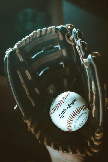 Baseball in a leather glove, possibly held by a person. The ball is marked 