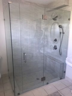 Glass-enclosed shower with marble-patterned walls
