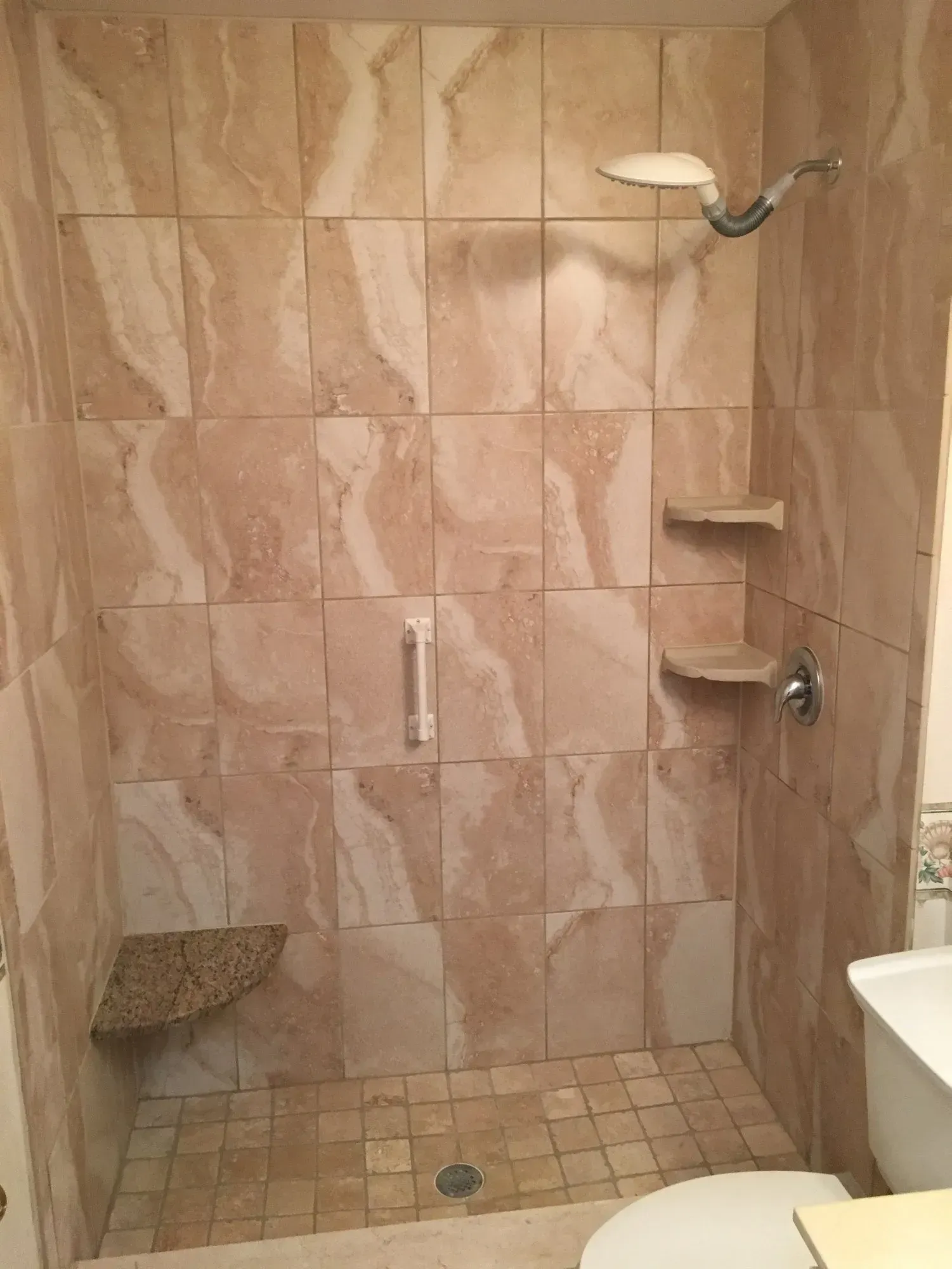 Shower with beige marble tiles and built-in corner shelves