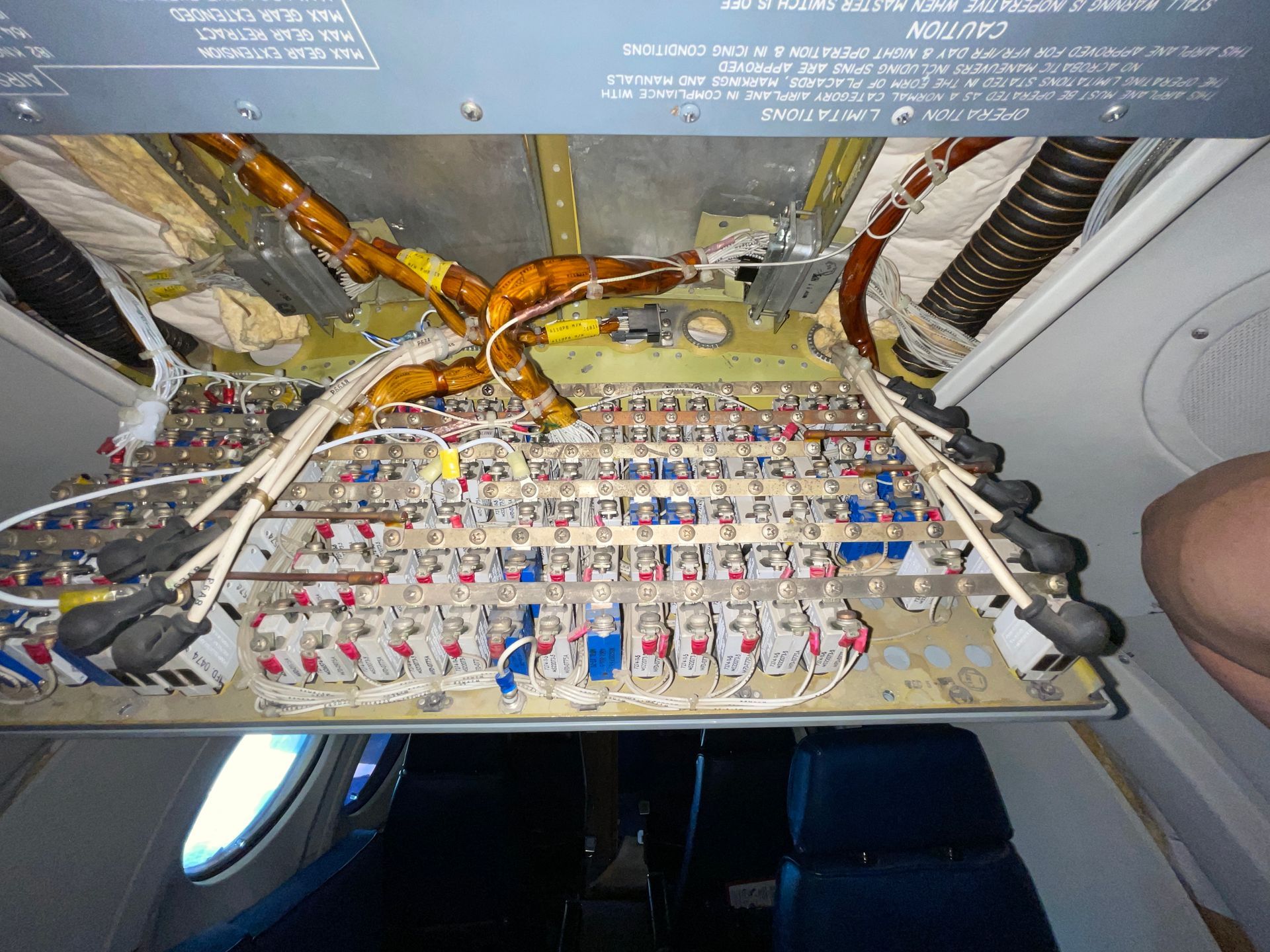 A bunch of wires are hanging from the ceiling of an airplane.